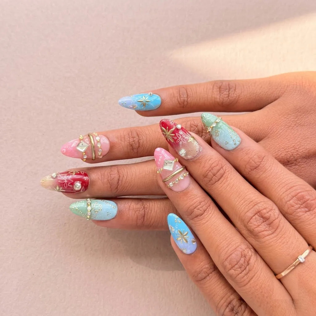 A close-up of a hand showcasing a pastel Christmas-themed nail art set with red and mint green holiday patterns, gold glitter accents, and small rhinestone details on long almond-shaped nails.
