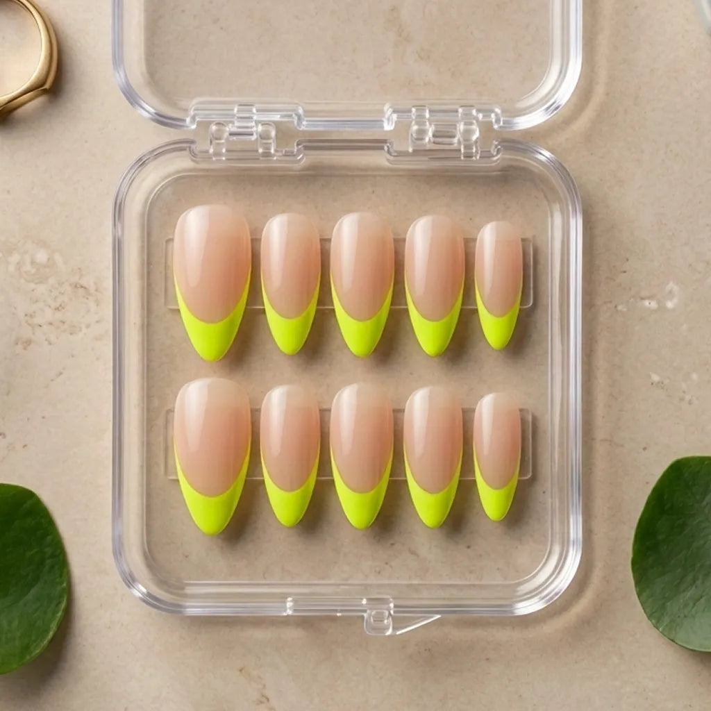 Ten false press-on nails arranged in a clear plastic case on a beige surface, with a French manicure design featuring a nude-pink upper half and a bright neon yellow-green lower half.