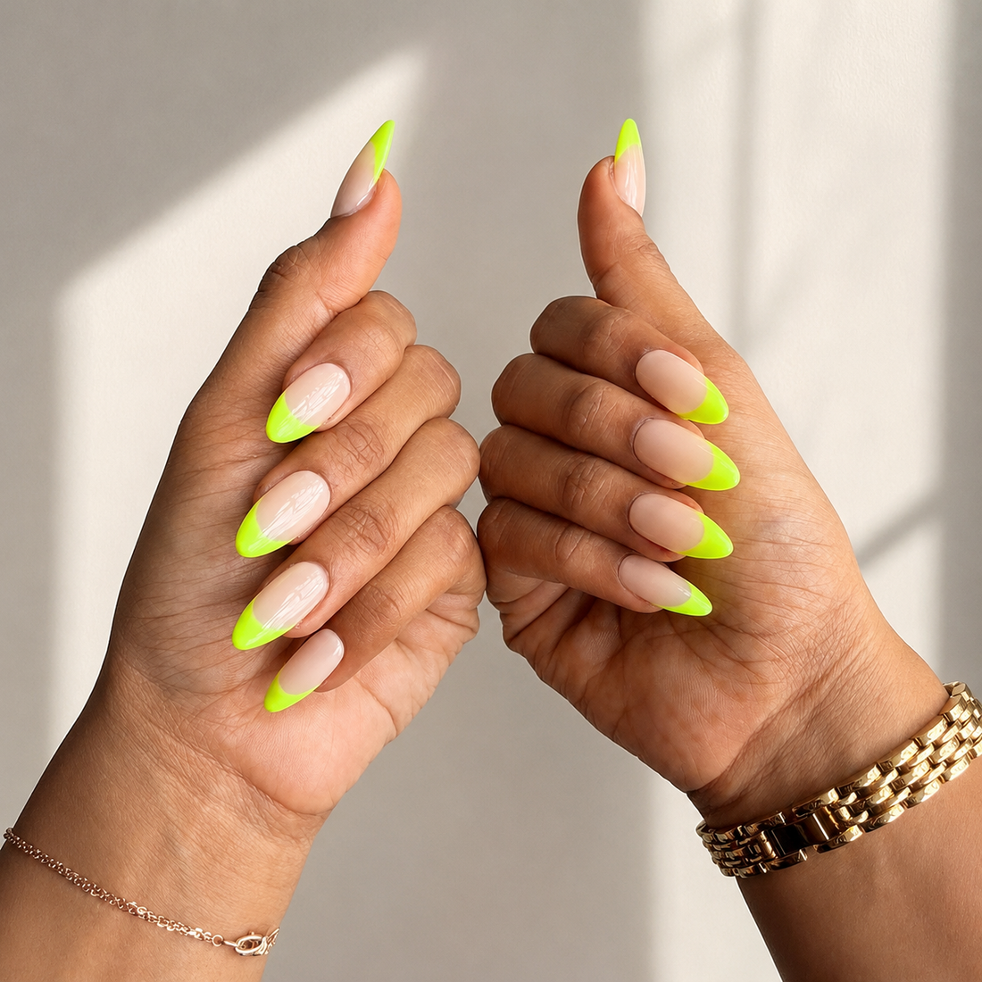 Ten false press-on nails arranged in a clear plastic case on a beige surface, with a French manicure design featuring a nude-pink upper half and a bright neon yellow-green lower half.