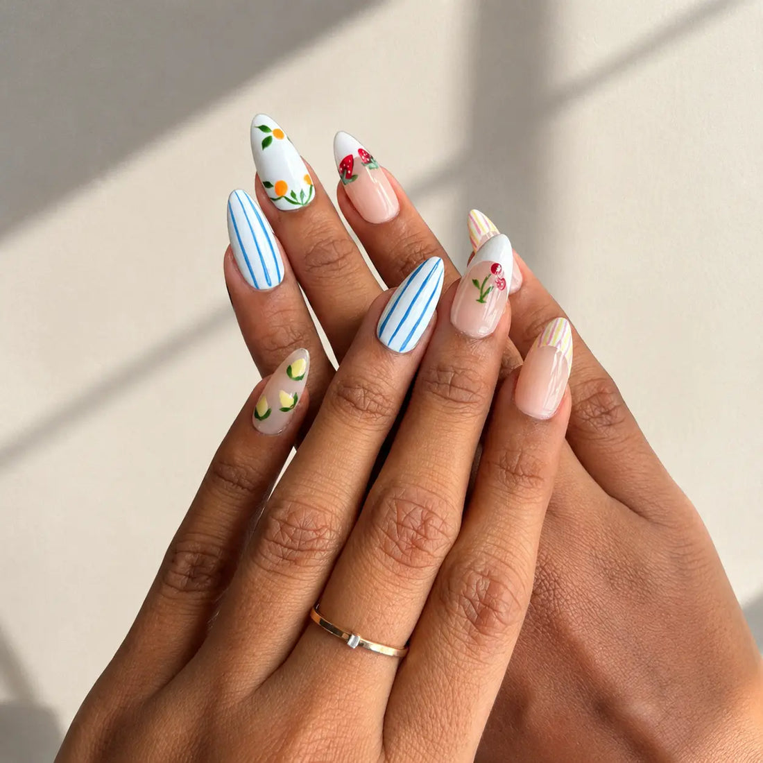 Set of nail art designs in a clear case with fruits on a pink background.Handmade reusable press on nails