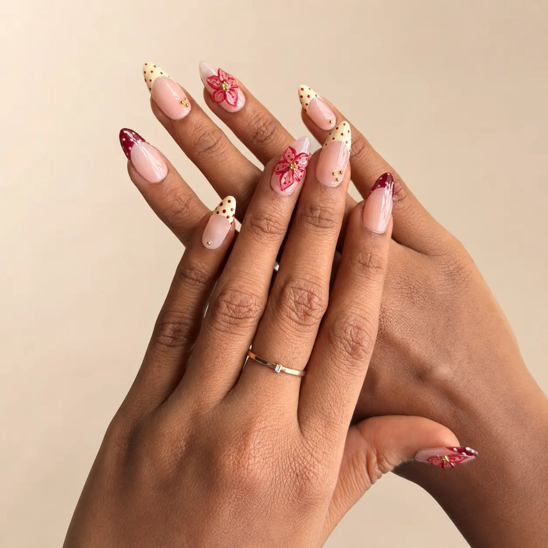 Set of decorative nail art in a clear case with floral and polka dot designs, surrounded by flowers and ribbons. Hand made reusable press on nails